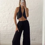 Pantalón negro de tiro alto, corte palazzo y cintura elastizada con cordón ajustable.