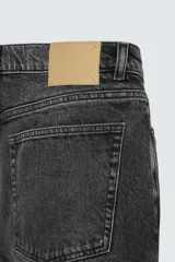 Pantalón de jean negro con efecto lavado, corte slim fit, cinco bolsillos y cierre frontal con botones.