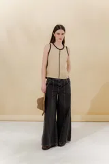 Pantalón de jean ancho de tiro medio bajo, color negro lavado, con costuras verticales marcadas en el frente y la espalda.