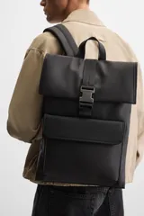 Mochila negra con acabado engomado, solapa y hebilla de liberación rápida. Tiene un bolsillo frontal con cierre imantado, asa de mano, dos asas de hombro ajustables, parte posterior acolchada y banda de sujeción para equipaje. El interior cuenta con un bolsillo con cierre y un compartimento para dispositivos electrónicos de hasta 13 pulgadas.