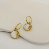 Par de aros dorados de acero quirúrgico hipoalergénico con baño en oro 18K y dije circular con incrustación de nácar y diseño de rayos de sol.