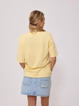Remera amarilla de algodón con estampado de playa hawaiana con palmeras, flores y tabla de surf.