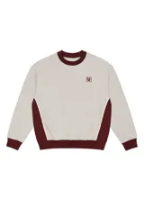 Buzo beige de corte oversize con bloques de color borgoña en los laterales, puños y cintura. Tiene cuello redondo y logo Vernal bordado en el pecho.