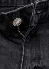 Pantalón de jean negro con lavado gastado, corte recto, tiro medio y terminación desflecada.