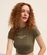 Blusa corta color verde militar, de rib de algodón, con cuello redondo, mangas cortas y estampado frontal con la frase "sensitive content inside".