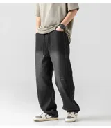 Pantalón de jean negro lavado, corte ancho y holgado, con cintura elástica y cordón ajustable. Presenta costuras verticales marcadas en los laterales exteriores de las piernas.