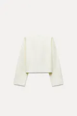 Chaqueta color crema de punto canalé con cuello redondo, manga larga y cierre frontal con botones marrones.