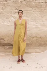 Vestido midi color amarillo mostaza, de lino, con botones frontales, sin mangas y corte recto.
