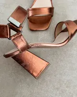 Sandalias plateadas con tira delantera, tobillera con hebilla y taco geométrico.