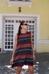 Vestido corto tejido a rayas horizontales en tonos beige, marrón, celeste y rojo. Diseño calado y corte holgado.