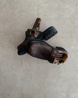 Zuecos negros de cuero con hebilla y tachas decorativas.