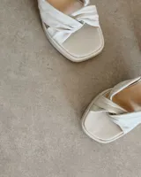 Sandalia de cuero vacuno color dorado, con plataforma y taco cuadrado. Presenta una tira delgada en el tobillo y detalle de nudo en la capellada.