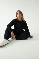 Sweater negro de punto suave con cuello redondo y hombros caídos.