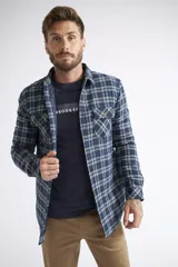 Sobrecamisa de viyela para hombre con estampado de cuadros en rojo y negro. Presenta cierre frontal con botones, bolsillos en el pecho con solapa y botón, y un interior capitoneado para mayor abrigo. Cuenta con un logo en grifa de cuero.