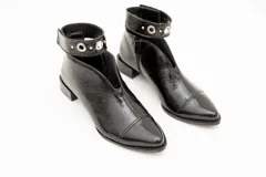 Botín de cuero color borgoña con taco bajo, corte en V en el empeine, pulsera con detalles metálicos y cierre lateral.