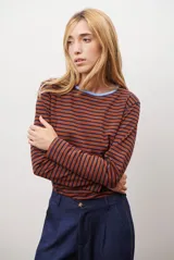 Remera de manga larga con diseño de rayas horizontales en azul y blanco, destacada por un cuello redondo en color bordó con costuras a la vista.