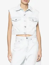 Chaleco de jean celeste claro, con cuello clásico, sin mangas, cierre frontal con botones metálicos y dos bolsillos con solapa en el pecho.