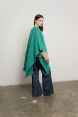 Ruana verde esmeralda de tejido de punto con flecos en el borde inferior.