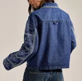 Campera de jean celeste con cierre frontal, cuello camisero, bolsillos con solapa y bordado de flores blancas.