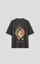 Remera gris con efecto lavado, corte holgado y estampa frontal con una mujer abrazando un leopardo, rodeada por una serpiente y hojas, con la leyenda 'La Fuerza'.