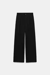 Pantalón de tiro alto color negro, confeccionado en hilatura con 22% de lino. Presenta bolsillos delanteros, detalle de pliegues, y cierre frontal con cremallera y botón.