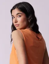 Blusa sin mangas color amarillo, con cuello redondo con frunces delanteros y abertura con botón en la espalda.