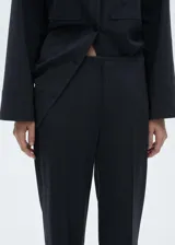 Pantalón de vestir negro con finas rayas verticales blancas, de tiro alto y corte recto.