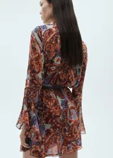 Vestido corto evasé con estampado paisley en tonos marrón, naranja y lila. Tiene cuello redondo con lazo, mangas largas con volantes, forro interior y cinturón desmontable.