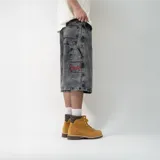 Bermuda de jean negro con efecto lavado, corte ancho y largo a la rodilla. Presenta bolsillos delanteros y traseros, etiqueta de marca en el bolsillo trasero y bordado rojo en la pierna derecha.