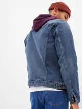 Campera de jean azul de corte clásico, con cuello camisero, bolsillos con solapa abotonados en el pecho y cierre frontal con botones metálicos.