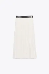 Falda midi color blanco, de tiro alto y corte evasé, con plisado vertical y cinturón negro con hebilla dorada.