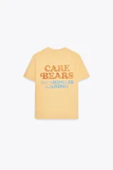 Camiseta color amarillo con efecto lavado, cuello redondo y mangas cortas. Estampado frontal con un oso de los Care Bears™ y la frase "free hugs".