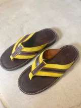 Chanclas de cuero color amarillo con detalles en turquesa y diseño cómodo.