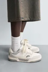 Zapatillas bajas de estilo skate color blanco y gris claro, con cordones y suela gruesa.