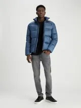 Campera acolchada en dos tonos de color azul, con relleno aislante, cuello alto y bolsillos laterales con cremallera, de la marca Calvin Klein.