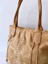 Bolso tipo tote de cuero color camel, con costuras a la vista y tiras de ajuste laterales.