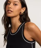 Musculosa negra de algodón con cuello redondo y frisos contrastantes en blanco en el cuello y las sisas.