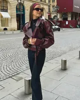 Campera corta de cuero sintético color borgoña, con cuello solapa, corte oversize, cierre cruzado con hebillas y cinturón.
