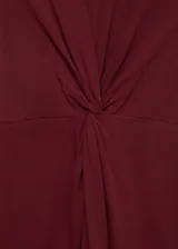 Vestido midi color borgoña, sin mangas y de corte recto, con cuello redondo y detalle de nudo drapeado en la cintura.