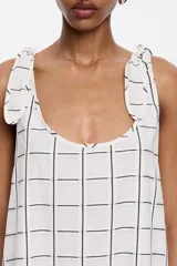 Vestido midi negro con estampado a cuadros blancos, corte recto, escote redondo y tirantes con lazos.