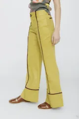 Pantalón acampanado color mostaza con ribetes marrones en los laterales y en el ruedo.