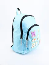Mochila celeste con ribetes negros, asa superior y correas acolchadas ajustables. Decorada con parches de letras y símbolos en colores brillantes y texturas variadas.