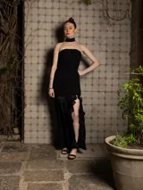 Vestido largo negro strapless con cuerpo fruncido y falda con tajo lateral y volados.