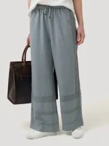 Pantalón gris de lino y viscosa con ajuste elástico y cordón en la cintura. Presenta broderie tono a tono en los laterales y en la parte inferior.