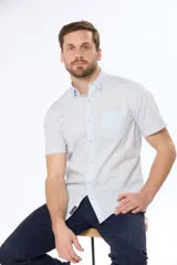 Camisa azul marino lisa de manga corta con cuello abotonado, cierre frontal con botones y bolsillo en el pecho. Confeccionada en algodón.