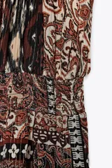 Vestido largo con estampado cachemir en tonos marrones, cuello halter con cordones con abalorios, nido de abeja elástico en la cintura, forro interior y tejido con hilo metalizado.