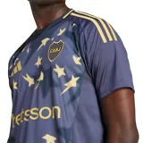 Camiseta de fútbol Adidas del Club Atlético Boca Juniors, modelo tercera equipación temporada 24/25. Diseño azul con estrellas doradas y detalles dorados en cuello y hombros. Incluye logo de Adidas, escudo del club y sponsor Betsson en el frente.
