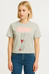 Remera color verde claro de algodón con cuello redondo y mangas cortas. Estampado frontal con dibujo de una pierna estilizada con zapato de tacón y corazones.