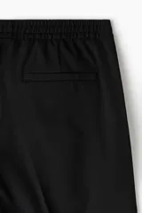 Pantalón jogger negro de vestir con corte slim fit, cintura elástica con cordón de ajuste, bolsillos laterales al bies y bolsillos traseros insertados.