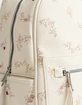 Mochila de cuerina color crema con estampado de flores bordadas, bolsillo frontal con cierre, correas regulables, manija superior, acceso con cierre superior, bolsillos laterales y tag de cuerina.